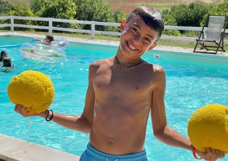 Al campo estivo inglese mare un ragazzo in piscina ha due palle gialle di spugna