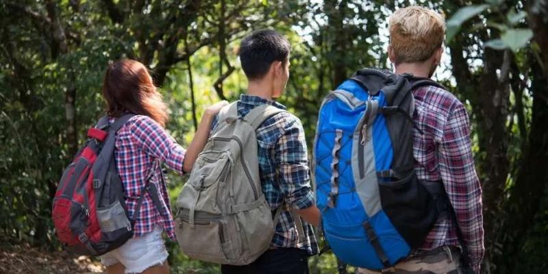 Ai viaggi organizzati Trentino tre ragazzi hanno degli zaini in spalla