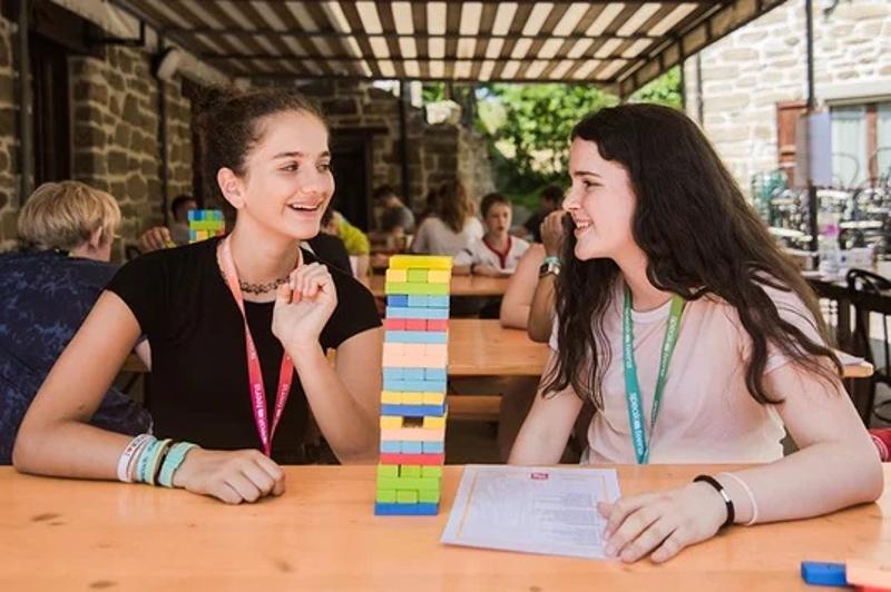 Al campo estivo inglese a Valbonella ci sono due ragazze che stanno facendo un gioco e sorridono