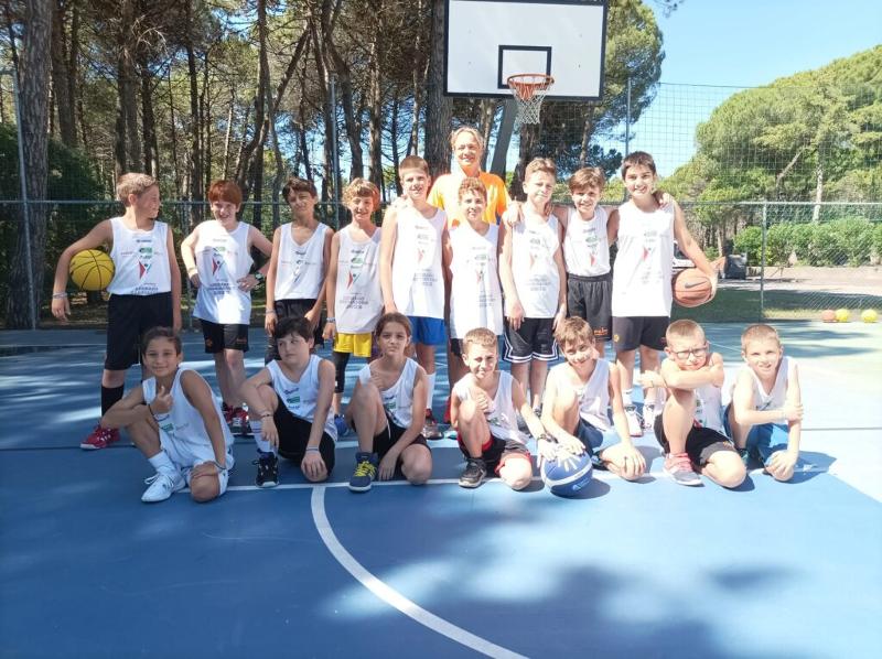 Al campo estivo di basket e minibasket a Lignano Sabbiadoro ci sono i bambini che stanno facendo una foto con l'allenatrice 
