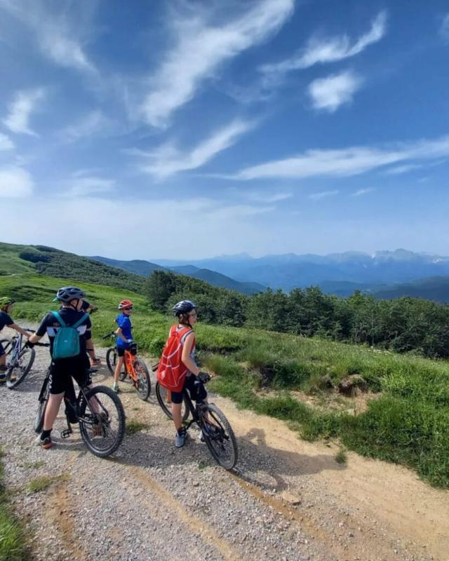 Ai viaggi per giovani a Trento un gruppo di bambini ammira il paesaggio davanti a loro con le loro biciclette