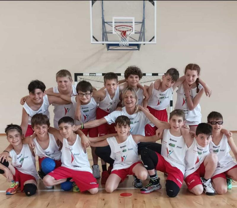 Al campo estivo multisport e minibasket a Ligonchio i bambini che giocano a basket sono riuniti e si stanno abbracciando facendo una foto di gruppo 