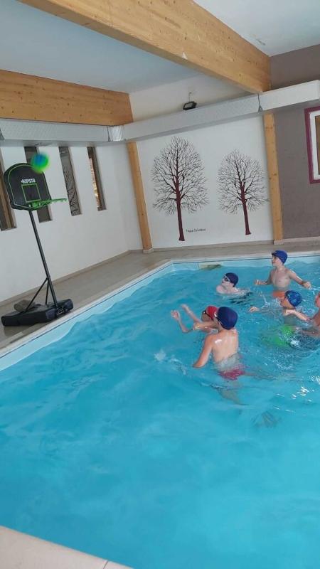 Al campo estivo multisport e minibasket a Ligonchio ci sono i bambini che stanno facendo il bagno in piscina e stanno giocando a waterbasket