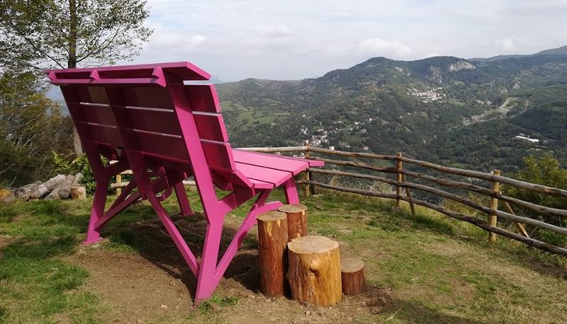 Ai viaggi organizzati Trentino c'è una panchina rosa di fronte ad una vista