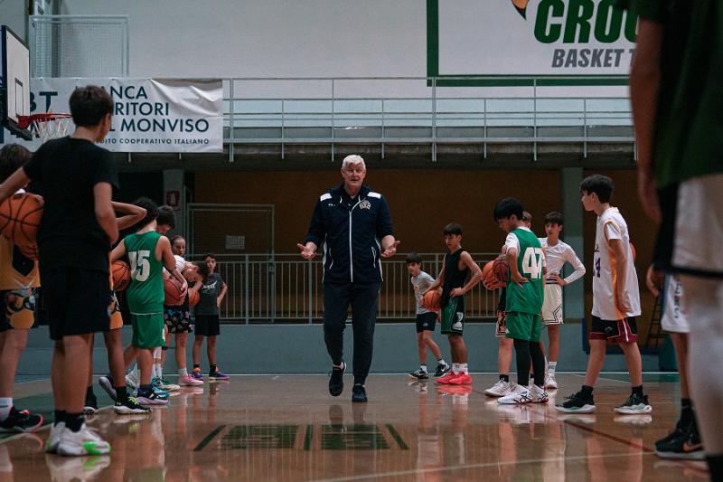 Al campo estivo di basket l'allenatore sta spiegando gli esercizi ai ragazzi