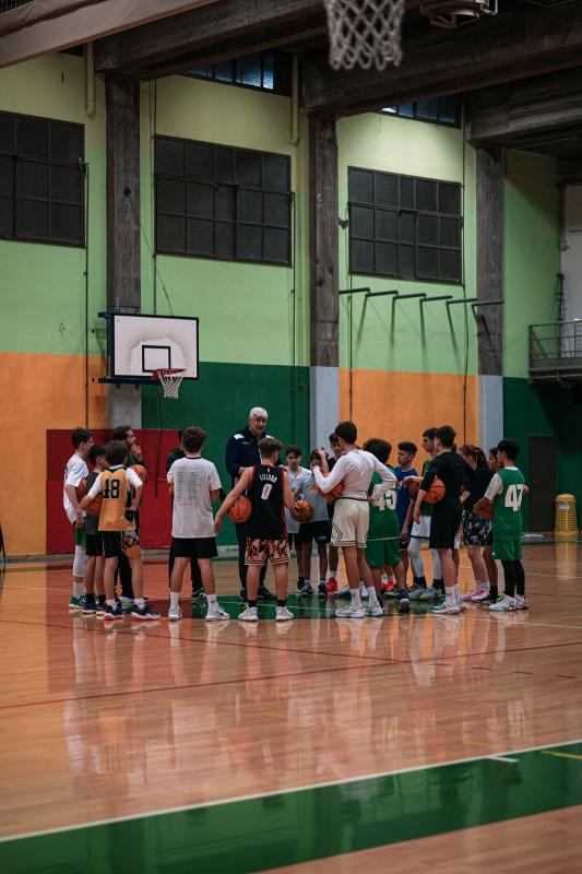 Al campo estivo di basket i ragazzi sono in cerchio attorno all'allenatore 