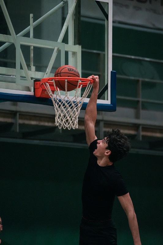 Al campo estivo di basket un ragazzo sta facendo una schiacciata a canestro 