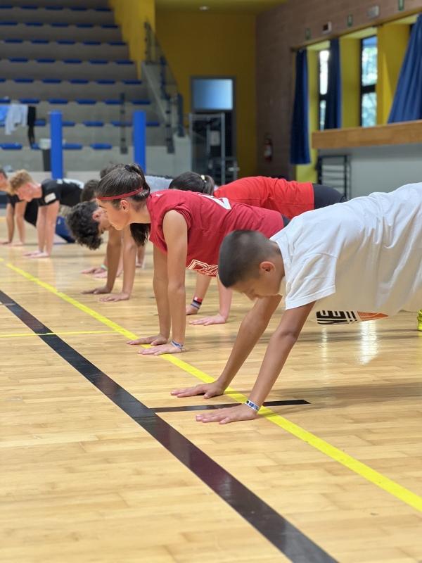 Al campo estivo di basket i partecipanti stanno facendo un esercizio in palestra 