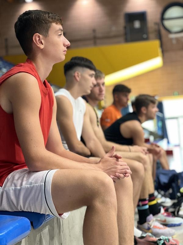 Al campo estivo di basket i ragazzi sono seduti in panchina ad osservare gli allenamenti 