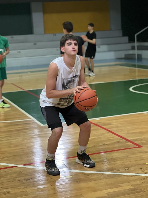 Al campo estivo di basket un ragazzo sta facendo un tiro a canestro 