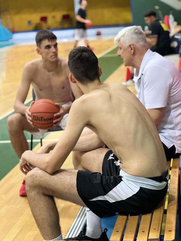 Al campo estivo di basket i ragazzi stanno ascoltando i consigli dell'allenatore 