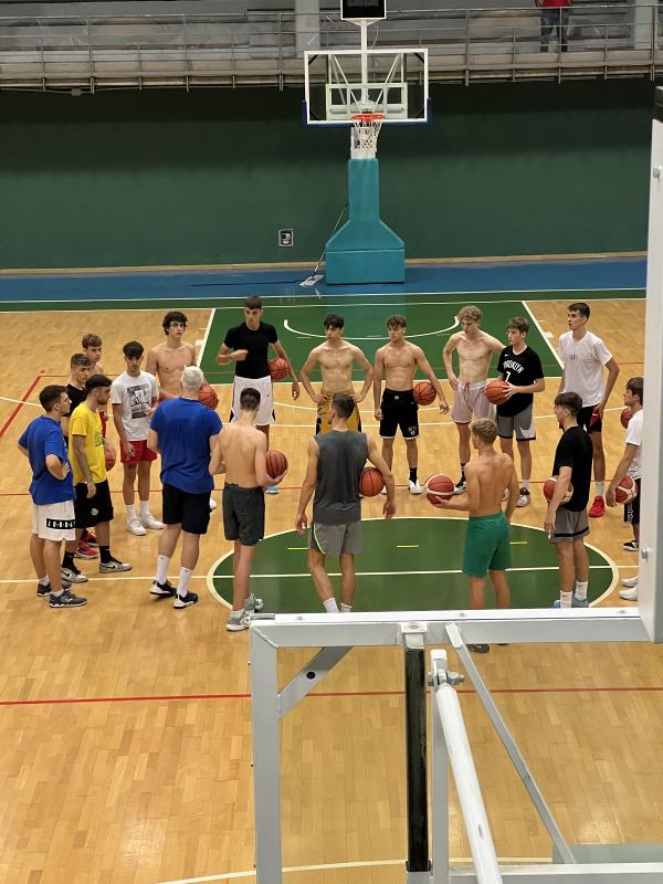 Al campo estivo di basket i partecipanti stanno facendo un allenamento in palestra 