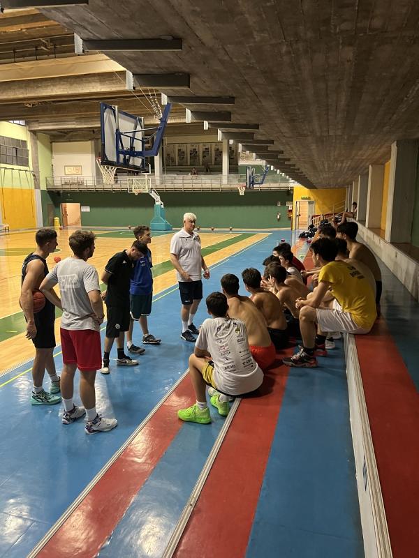 Al campo estivo di basket i partecipanti stanno ascoltando i consigli dell'allenatore