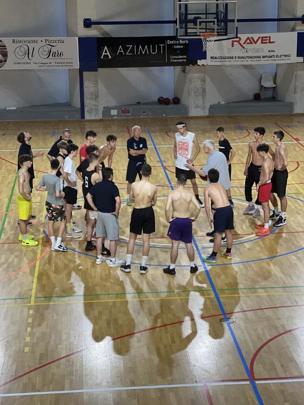 Al campo estivo di basket l'allenatore sta esponendo la tecnica di gioco ai ragazzi 