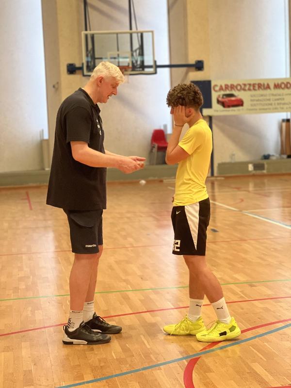 Al campo estivo di basket l'allenatore sta parlando con uno dei partecipanti 