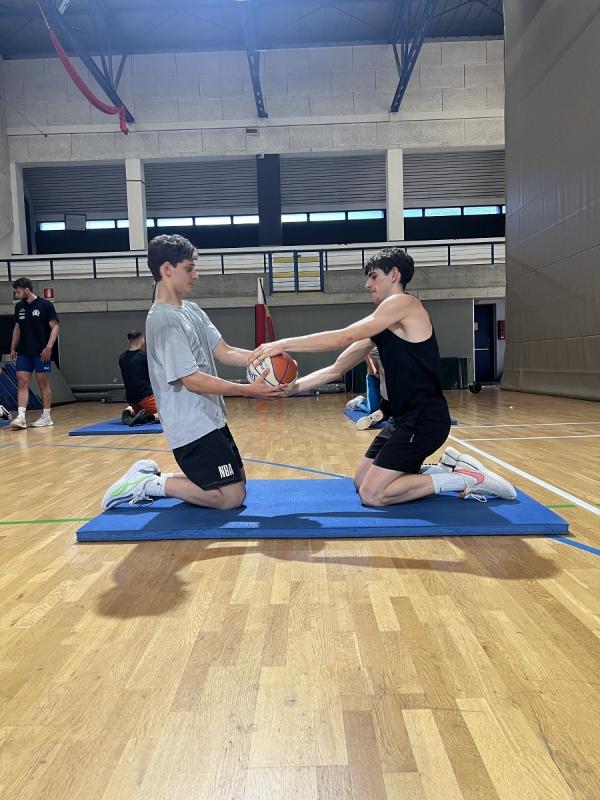 Al campo estivo di basket due ragazzi stanno facendo un esercizio di coppia