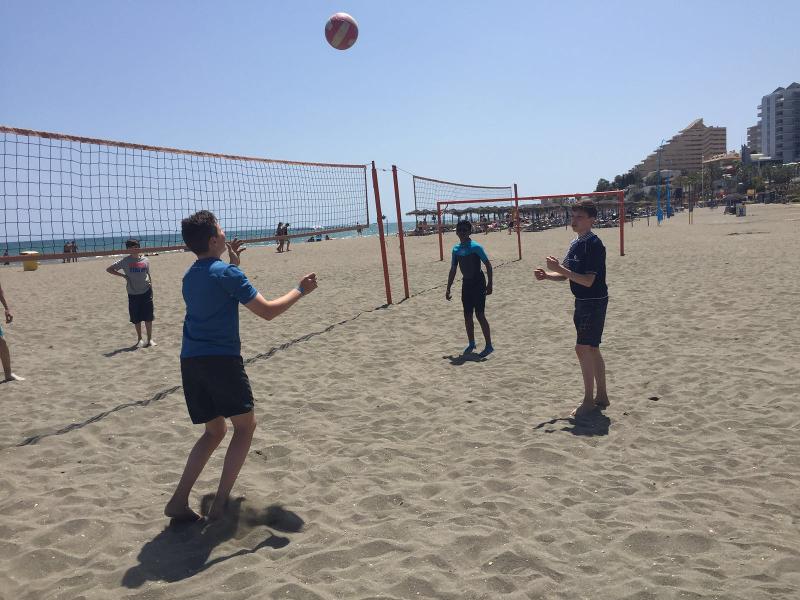 Ai soggiorni linguistici Malaga tre ragazzi giocano a beach volley in spiaggia