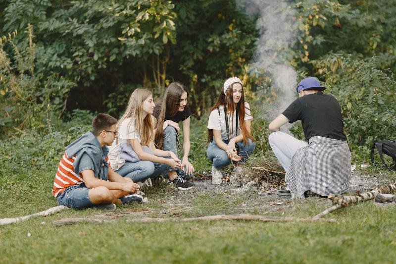 Al campo estivo avventura Merano ci sono dei ragazzi  nel bosco che fanno un fuoco 