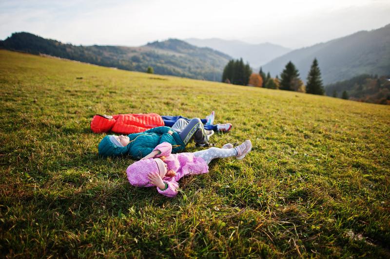 Al campo estivo avventura Merano ci sono tre bambini che sono sdraiati su un parto verde