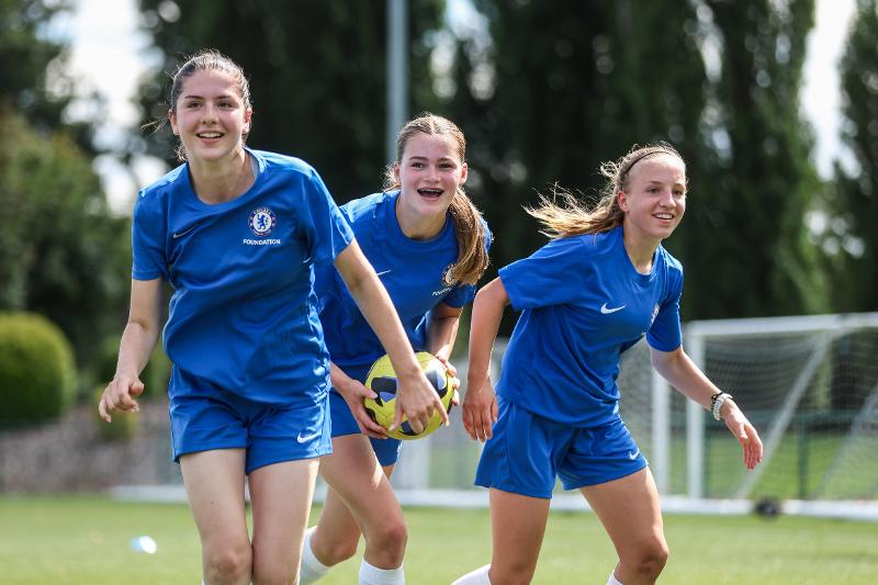 Tre ragazze sorridono al campo estivo calcio Inghilterra