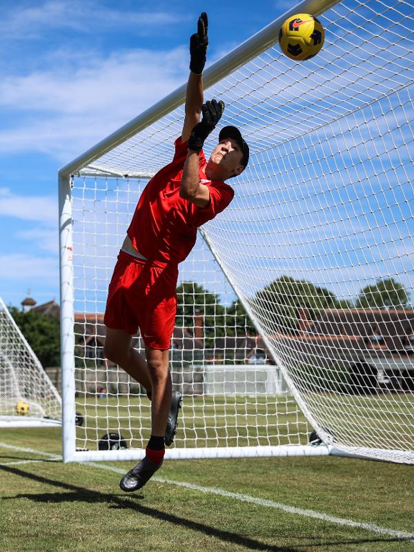 Un ragazzo del campo estivo calcio Inghilterra si lancia in tuffo per parare un pallone