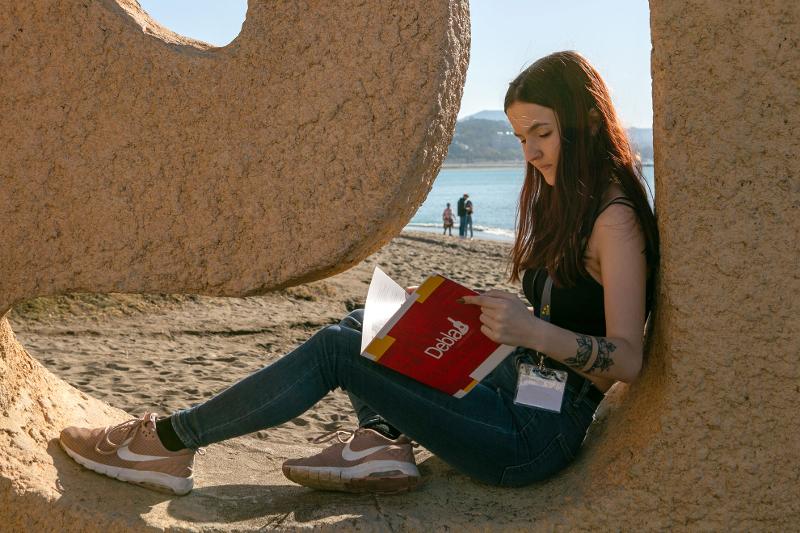 AL soggiorno linguistico spagnolo una ragazza sta studiando in spiaggia 