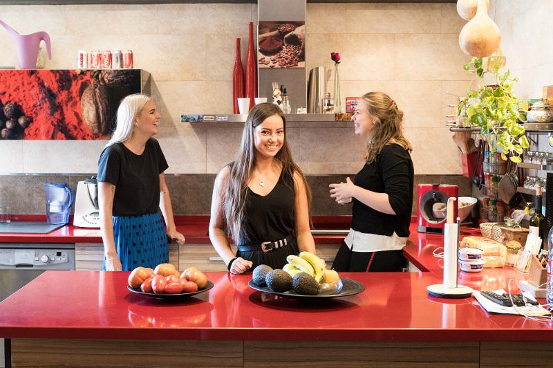 Al soggiorno linguistico spagnolo tre ragazze sono insieme in cucina e stanno parlando tra di loro 