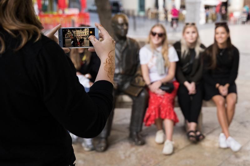 Al  soggiorno linguistico spagnolo una ragazza sta scattando una foto ad altre ragazze sedute al fianco di un monumento 