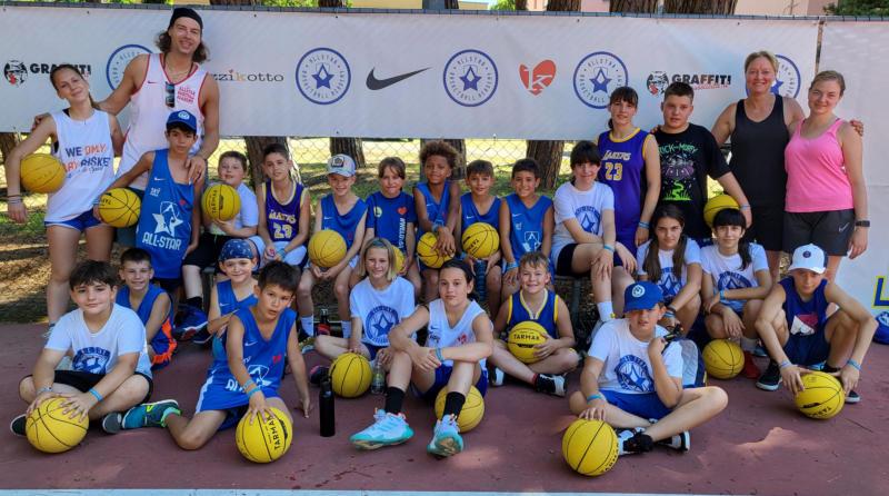Gruppo di bambini vestiti da basket e con palloni gialli al campo estivo All Star basket a Lignano Sabbiadoro