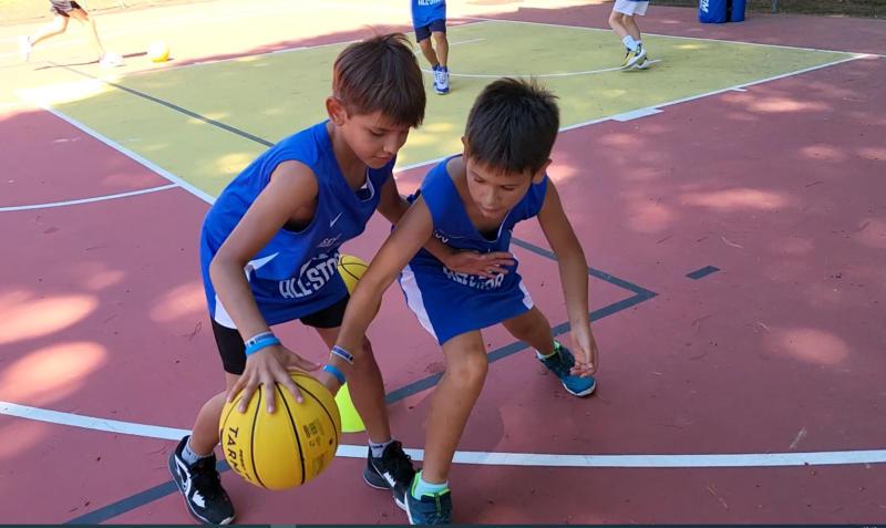 Due bambini si placcano mentre giocano a basket al campo estivo All Star basket a Lignano Sabbiadoro