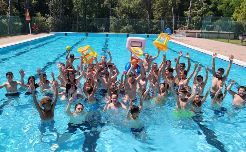 Gruppo di bambini sorride e alza le braccia al campo estivo All Star basket a Lignano Sabbiadoro