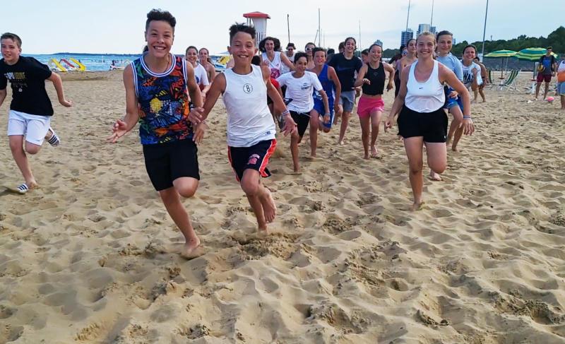 Ragazzi in spiaggia corrono allegri al campo estivo All Star basket a Lignano Sabbiadoro
