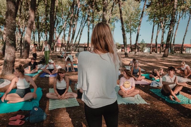 Al campo estivo internazionale surf Vieux Boucau un gruppo di persone pratica yoga all'aperto
