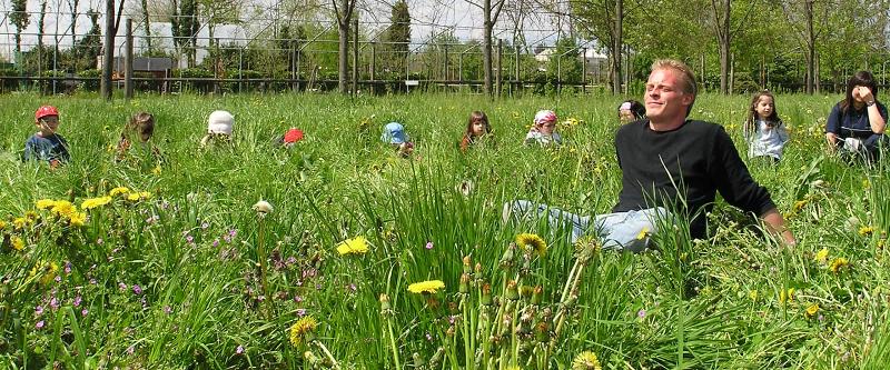 Al campo estivo naturalistico e di equitazione a Vivaro i bambini sono seduti sull'erba e prendono il sole