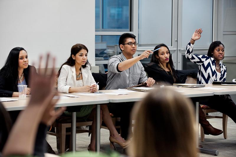  un gruppo di ragazzi partecipa ad una lezione di inglese in cui uno studente con la mano alzata interagisce con l'insegnante