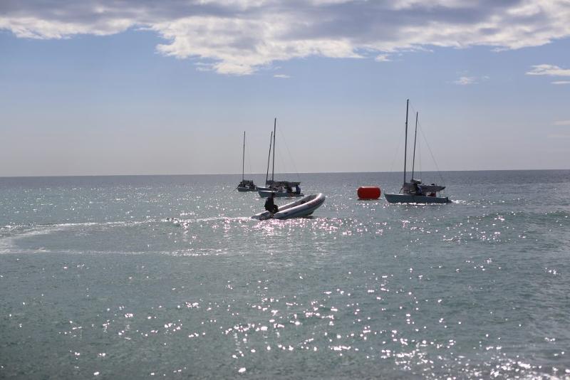 Vista sul mare calmo durante una giornata di sole con quattro barche all'orizzonte