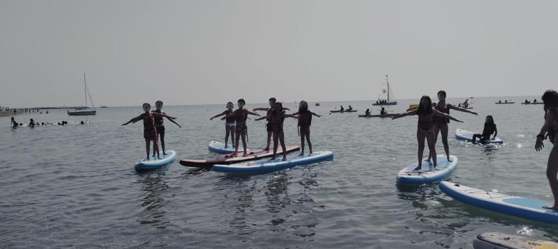 Un gruppo di ragazzi in equilibrio su una tavola da sup partecipa ad una lezione di sup in mare