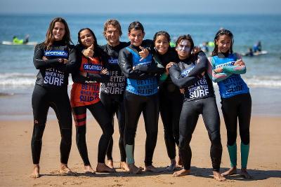 Sette ragazzi in riva al mare con la tuta da surf si fanno scattare una foto al campo estivo surf