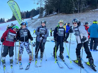 Cinque ragazzi del campo invernale indossano tuta e sci e si trovano su una pista