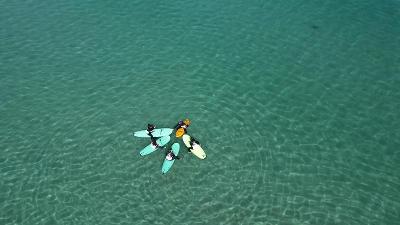 Cinque partecipanti del campo estivo surf si dispongono a cerchio con le tavole e gli viene scattata u7na foto